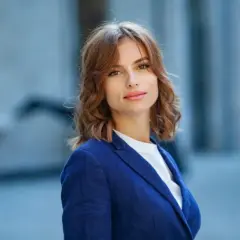Elegancka Jolanta w granatowej marynarce, gotowa na świętowanie imieniny. Uśmiecha się ciepło, a jej włosy delikatnie falują.