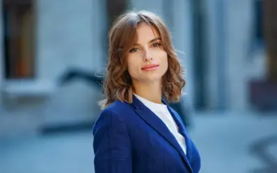 Elegancka Jolanta w granatowej marynarce, gotowa na świętowanie imieniny. Uśmiecha się ciepło, a jej włosy delikatnie falują.