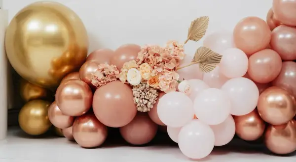Złote i różowe balony z kwiatami i liśćmi wachlarzowymi.