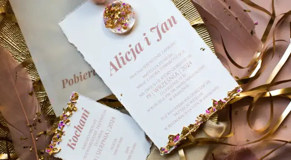 Eleganckie zaproszenia ślubne z ozdobnymi piórami i złotymi elementami.