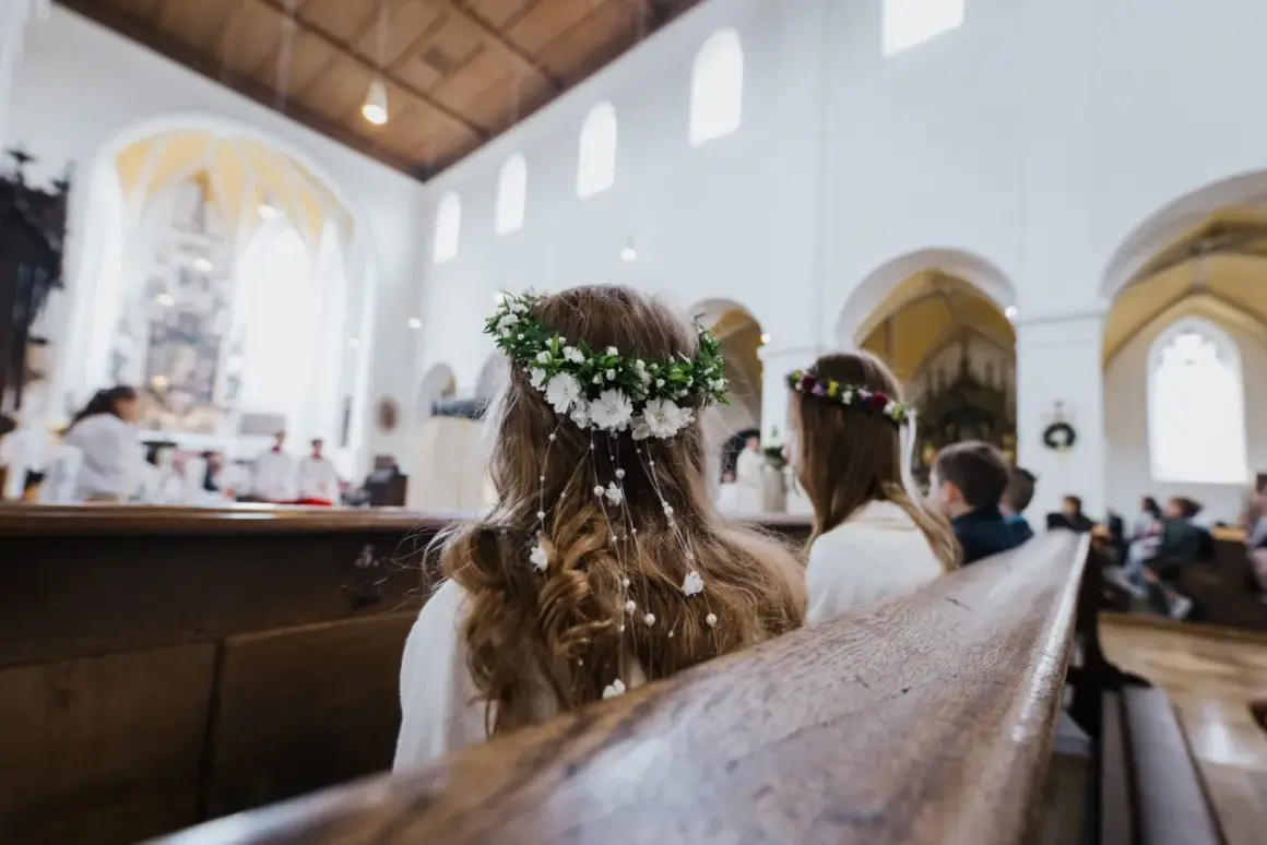 Dwie dziewczynki w wiankach siedzą w kościele podczas komunii.